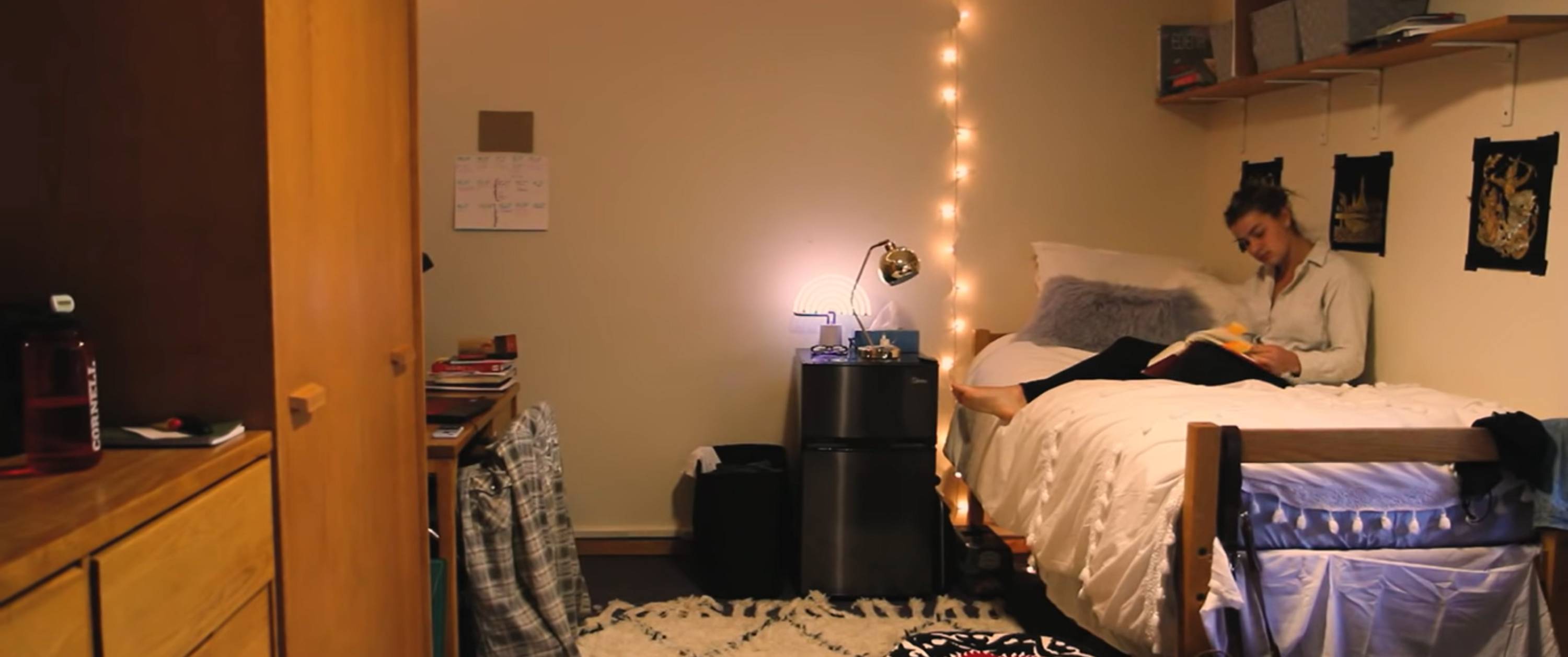 A student sits on her bed in her dorm room