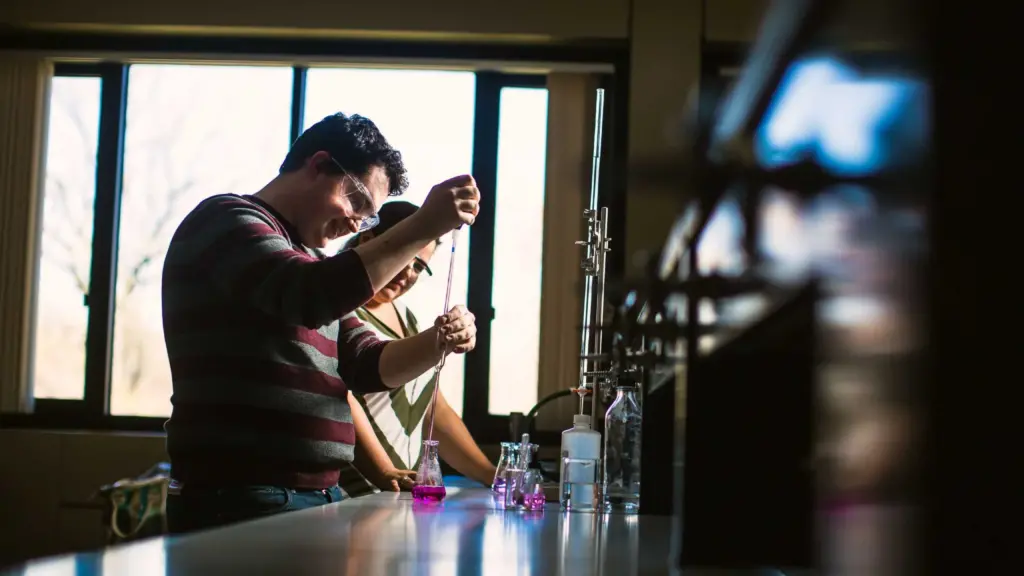 Two students work at a table in a lab