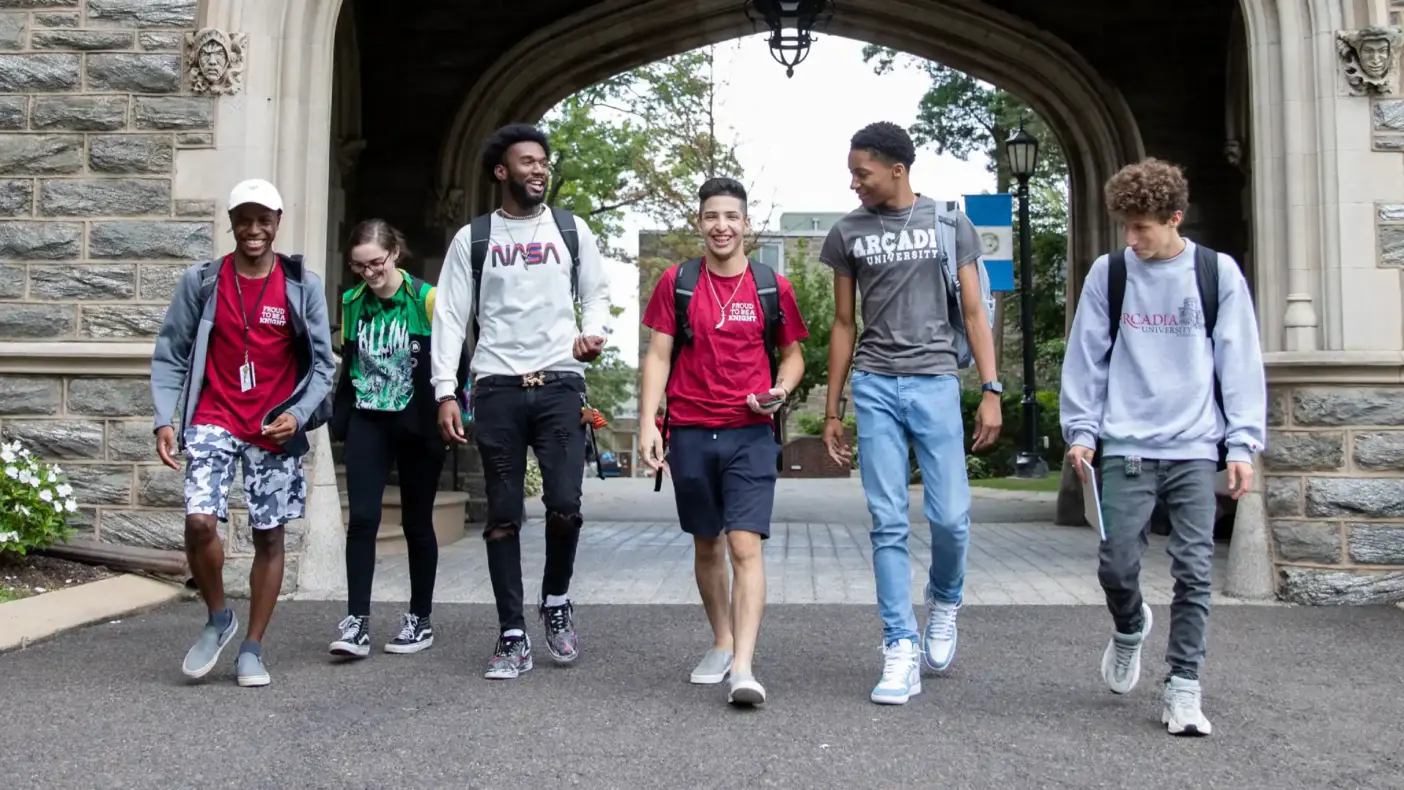 Six gateway students in front of Castle, smiling and walking towards the camera.