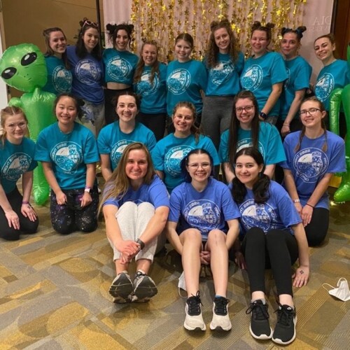 A group of students in three rows wears matching blue t-shirts