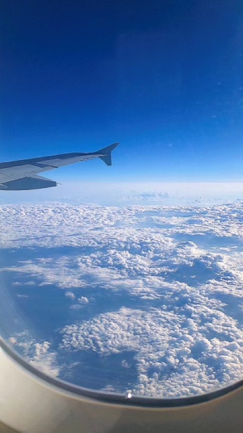 a photo from a plane window showing clouds and the wing of a plane