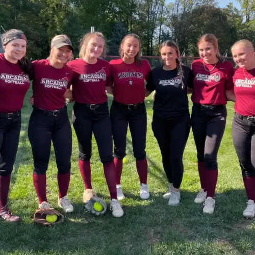 Members of the softball team stand in a line.