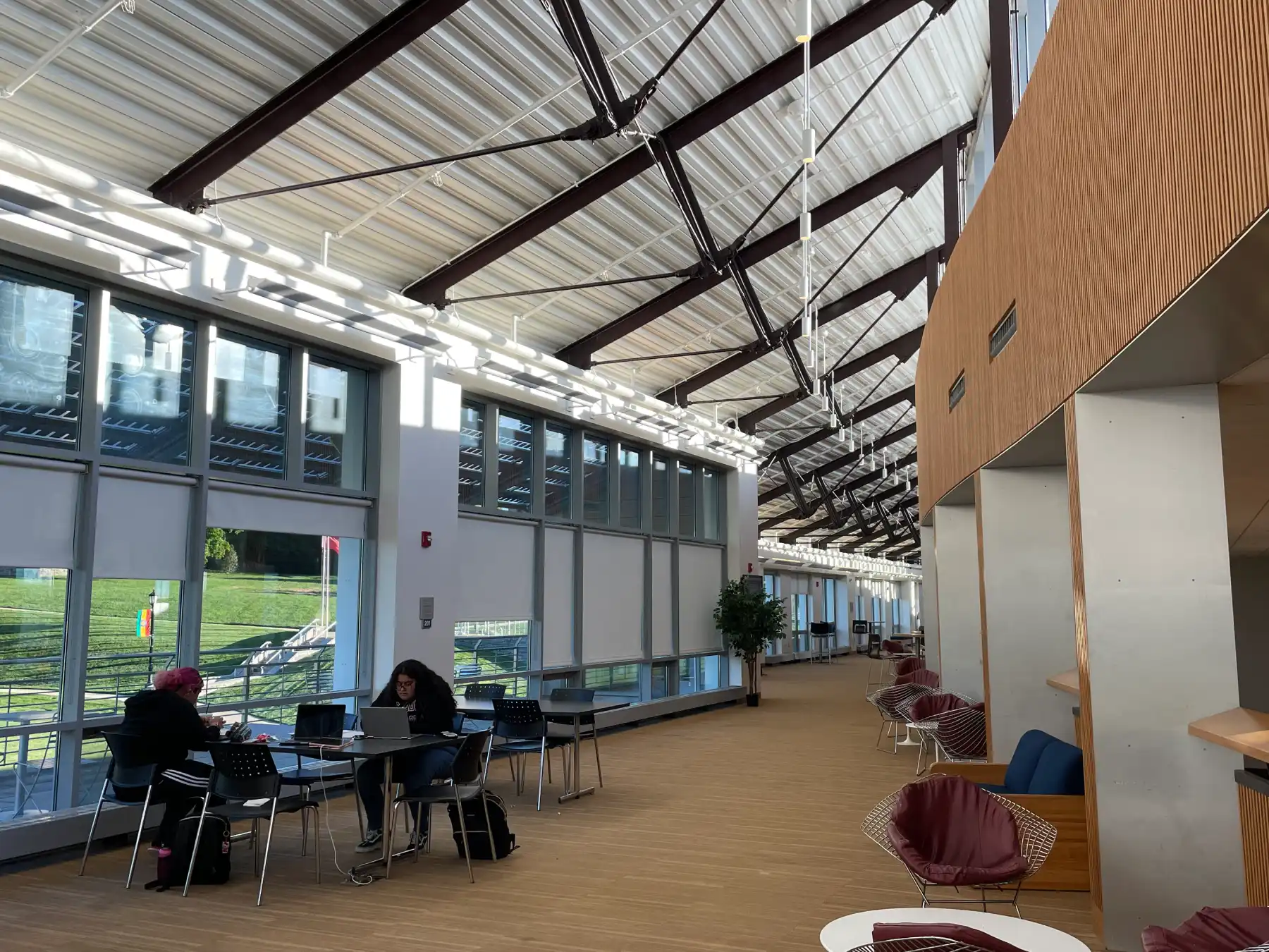 The second floor of University Comms, where two students sit facing each other at a table doing work on their laptops