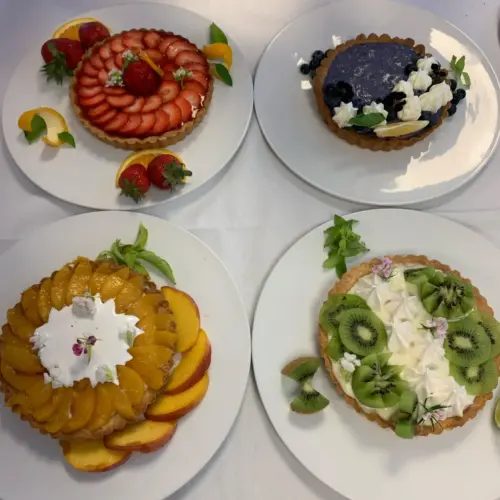 Four professional looking dessert tarts each on its own plate