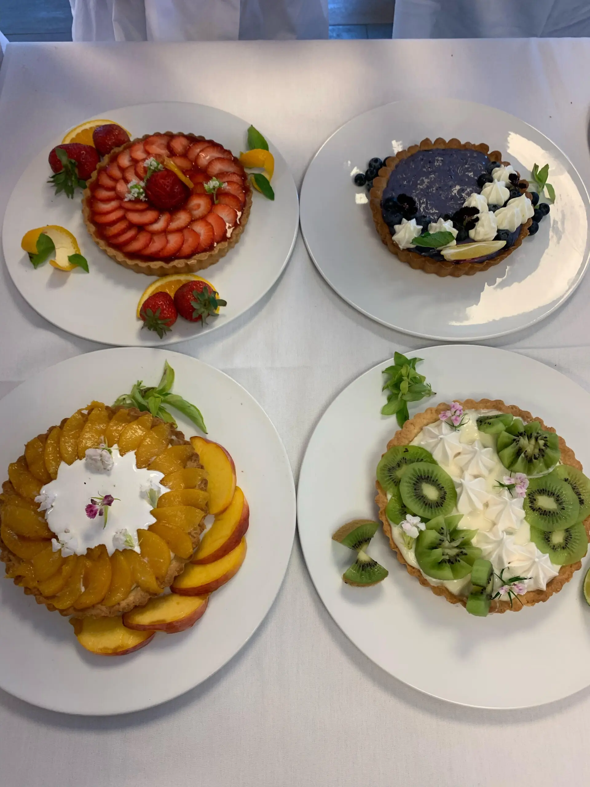 Four professional looking dessert tarts each on its own plate