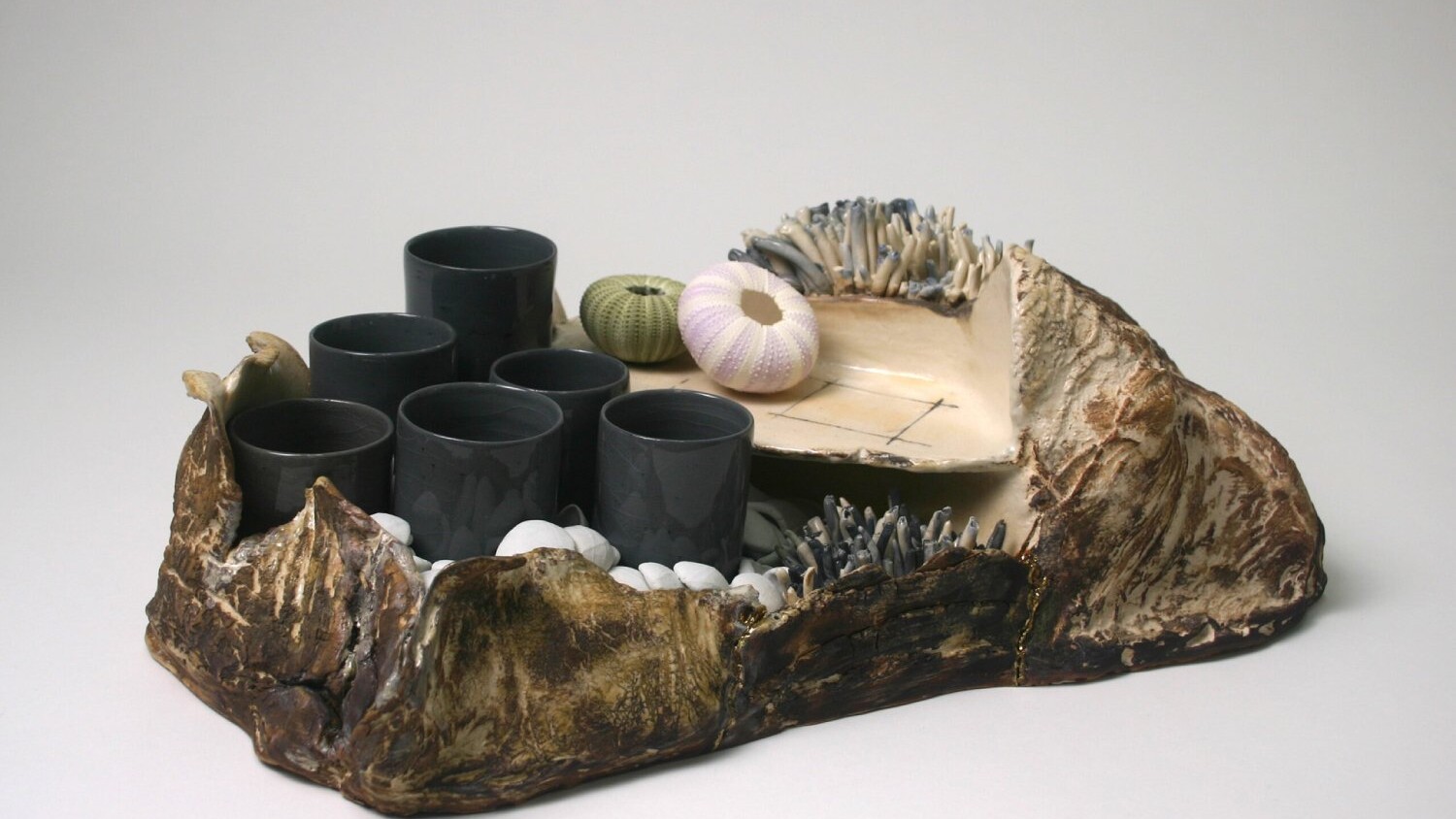 a collection of ceramic cups and natural materials as displayed in the exhibition