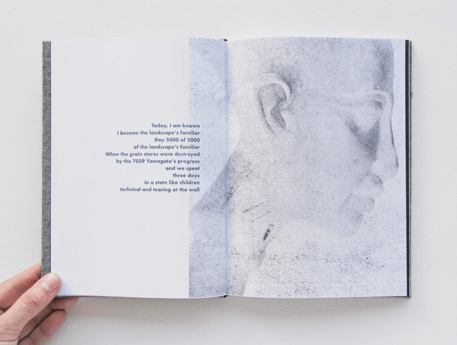 a person holds open a book with a ghostly image of a face on the right page and text on the left