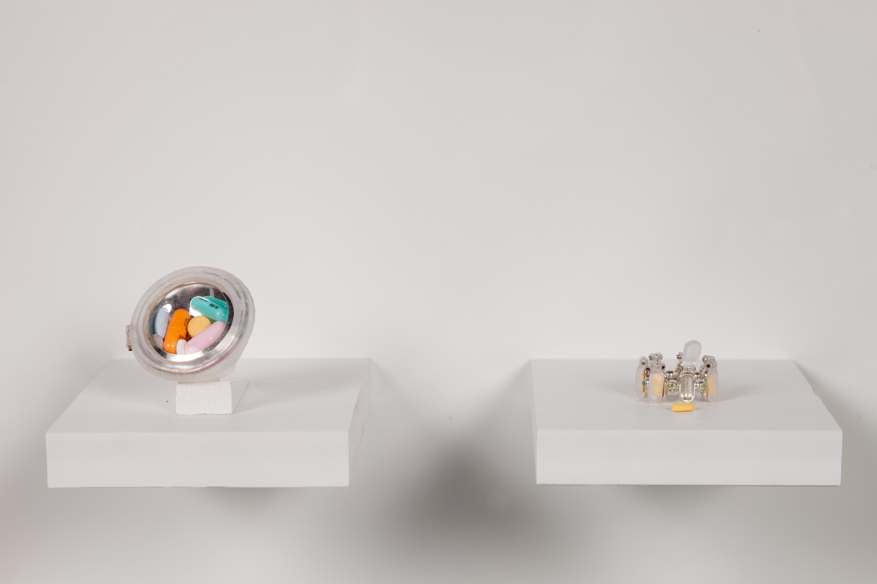 two rings made of silver and resin on small shelves, the rings contain prescription medication