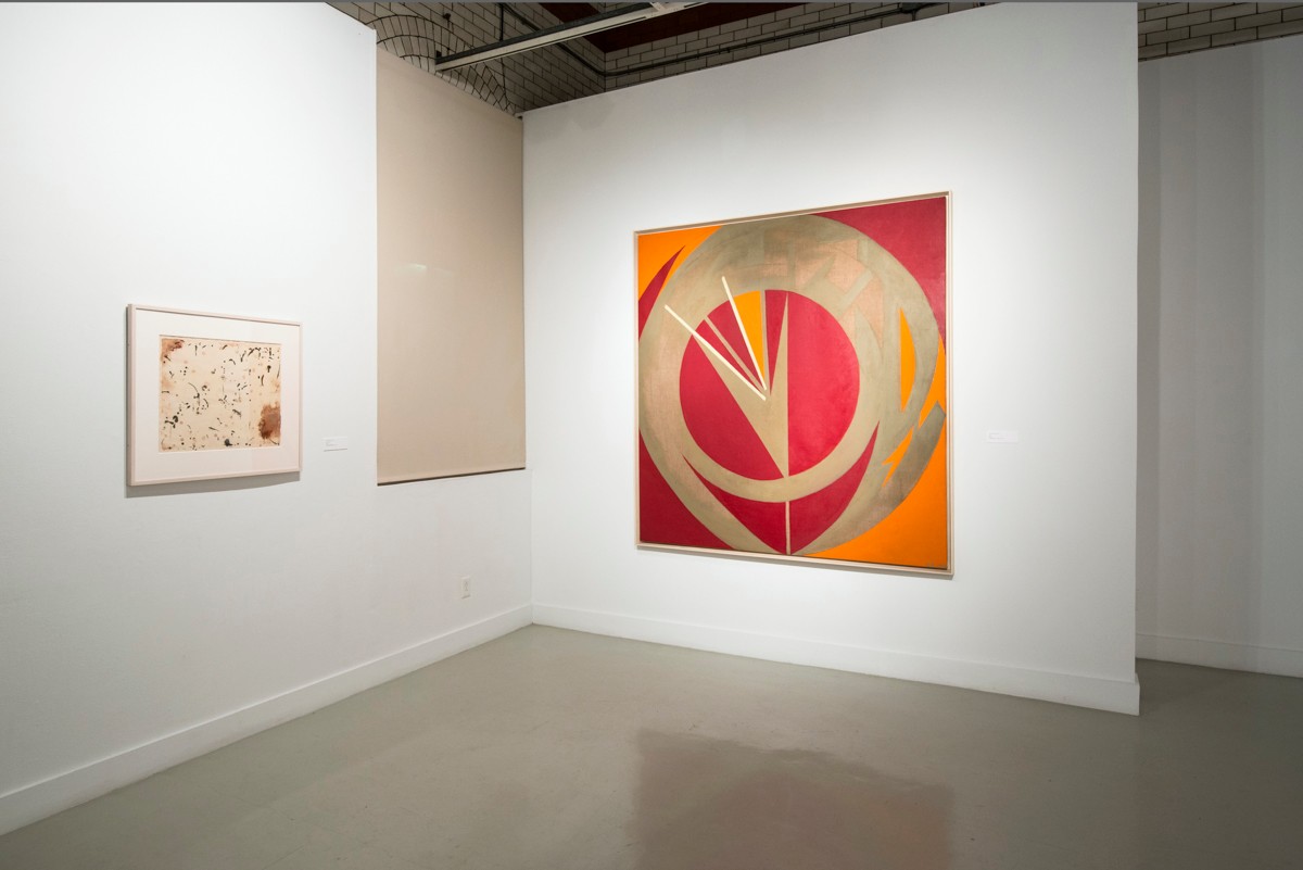 Installation view from "Threading the Maze" featuring two paintings with hues of orange, gold, red, and beige.