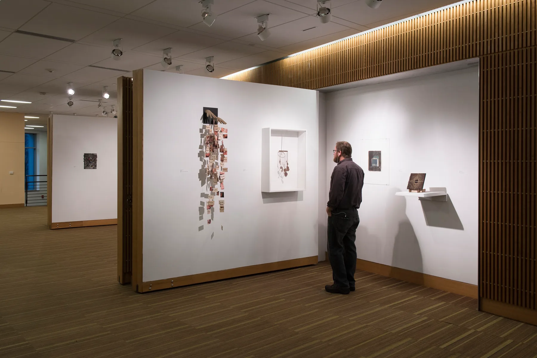 A person looking at an art exhibition with the lights dimmed down