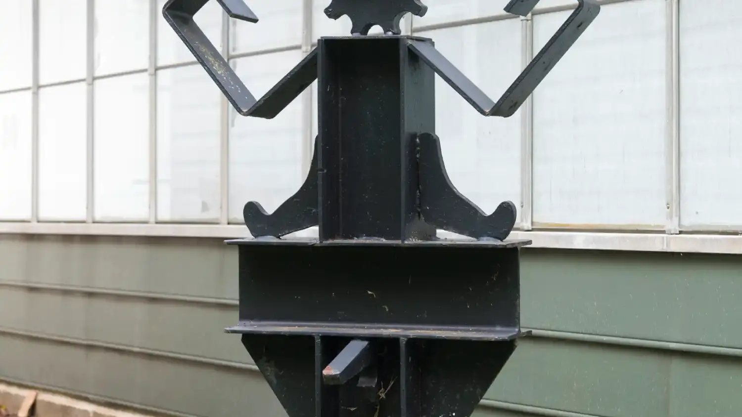 A metal sculptures that resembles a black steel robot with red eyeglasses