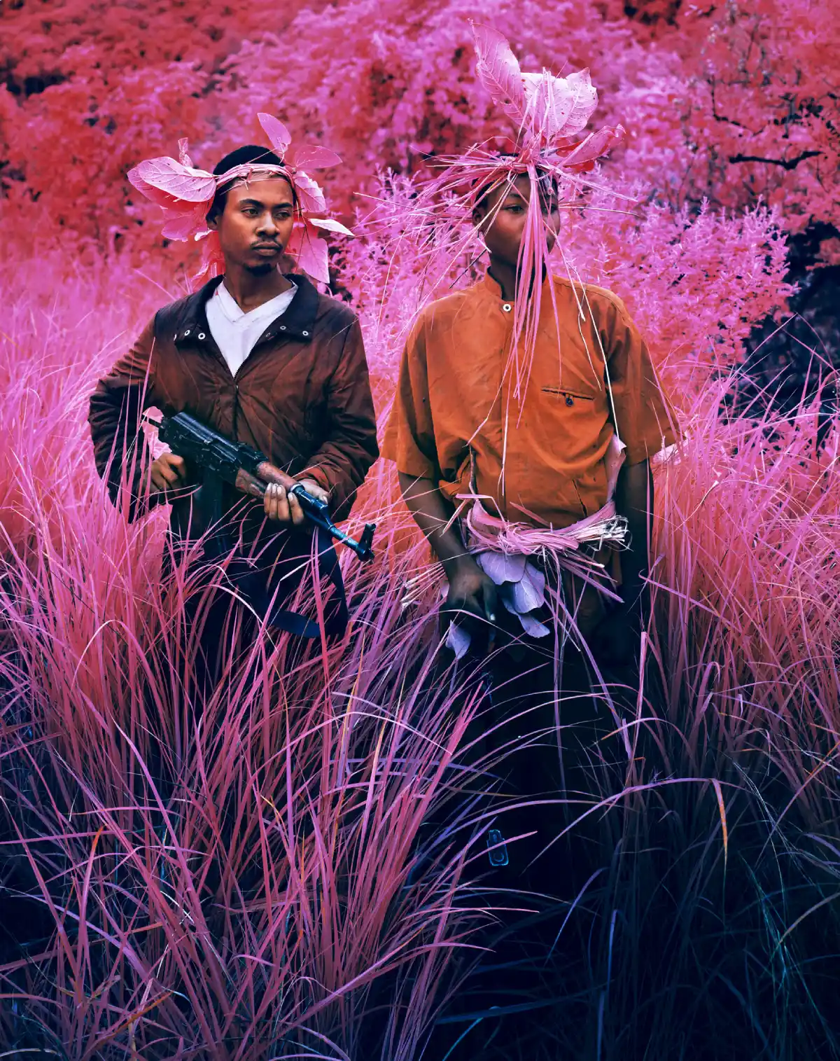 a photograph of two young men in a landscape taken using false color film that makes green objects appear in shades of pink and red