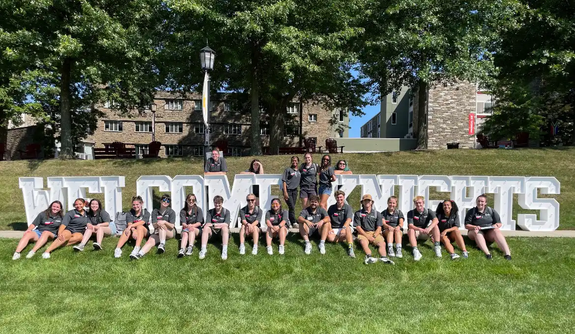 Fall orientation leaders around a Welcome Knights sign on Haber Green