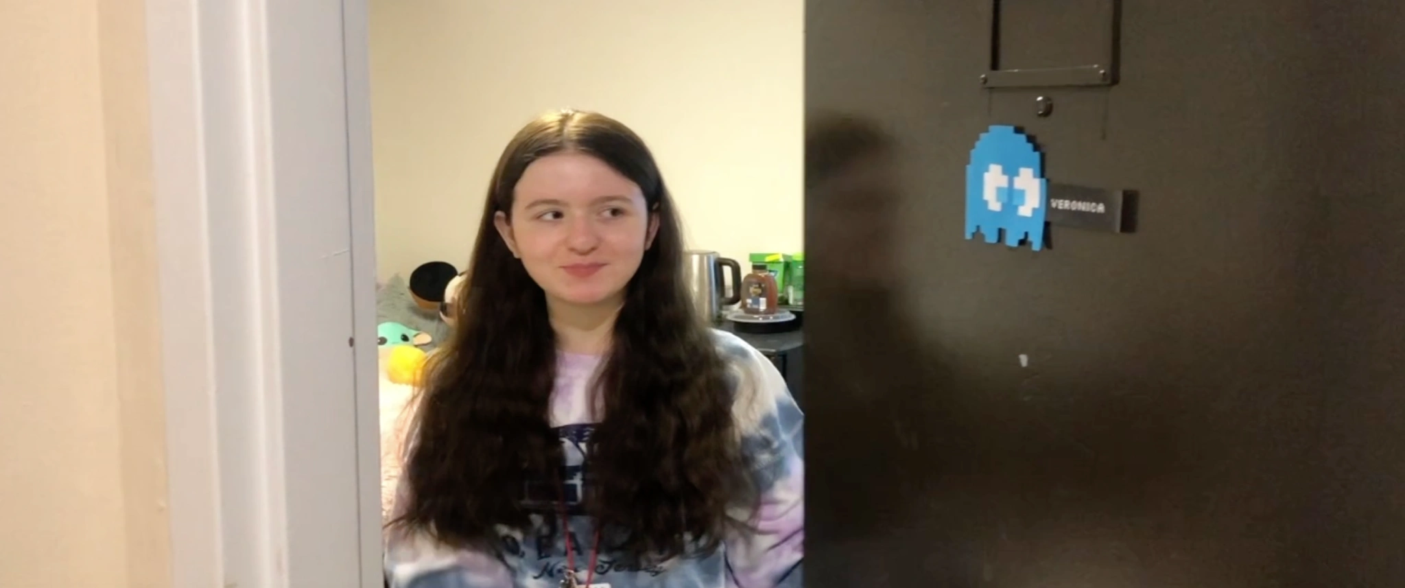 a student named Veronica looks out from the door of her residence hall