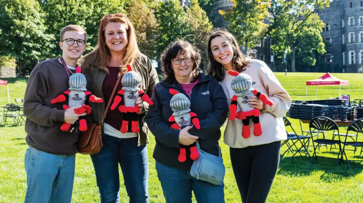 A family smiling at the camera while carrying an Arcadia Archie plushie
