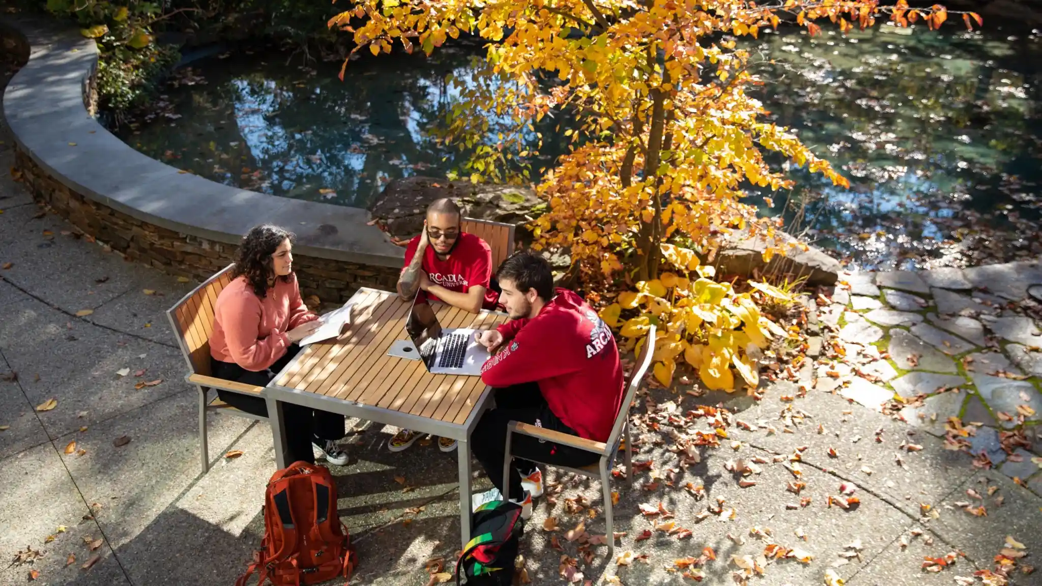 Students sit at a table at Easton Pond in the fall.