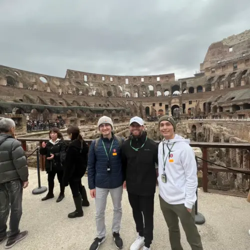 Three people stand in front of the Colisseum