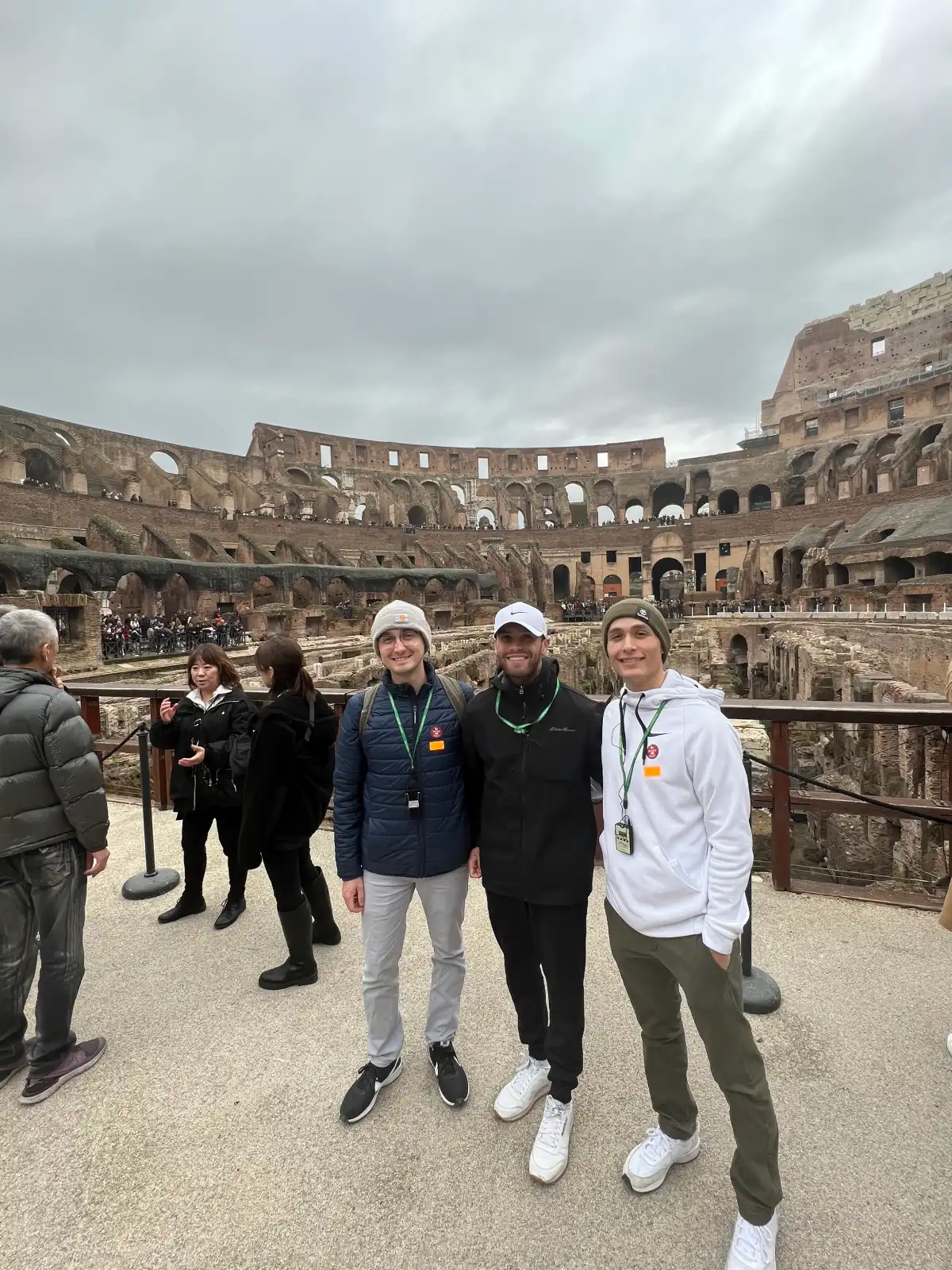 Three people stand in front of the Colisseum