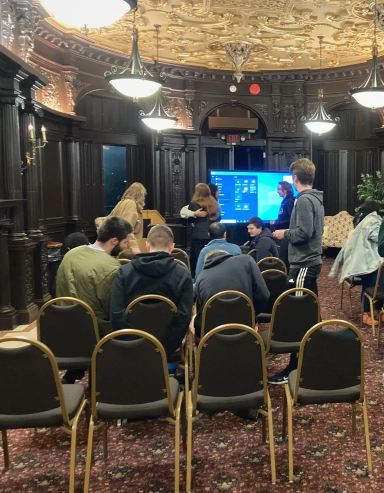 People are seated in a room in the Castle facing a TV monitor