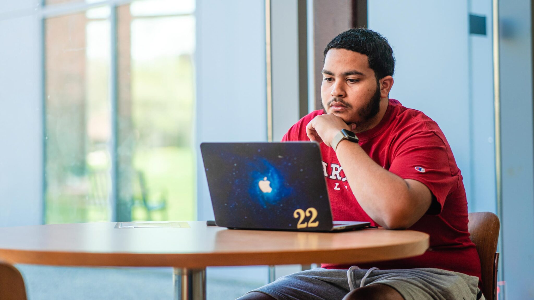 Student works in the library on his laptop