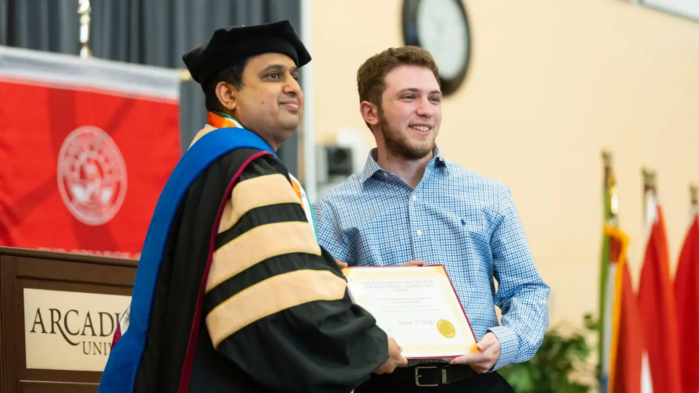 A student accepts an award from an Arcadia academic official at the Honors Convocation celebration.