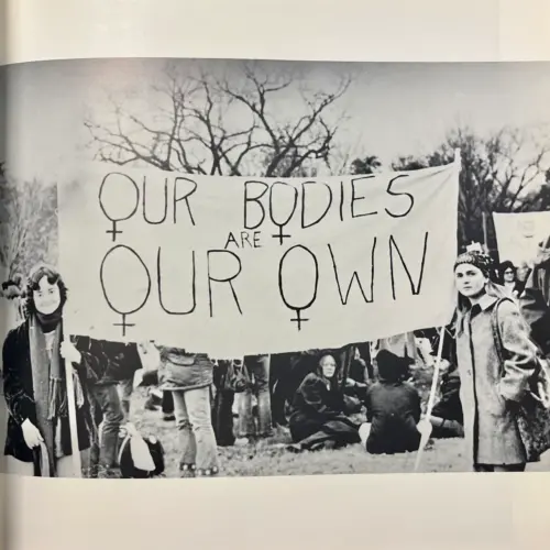 Two women holding a banner stating "our bodies are our own".