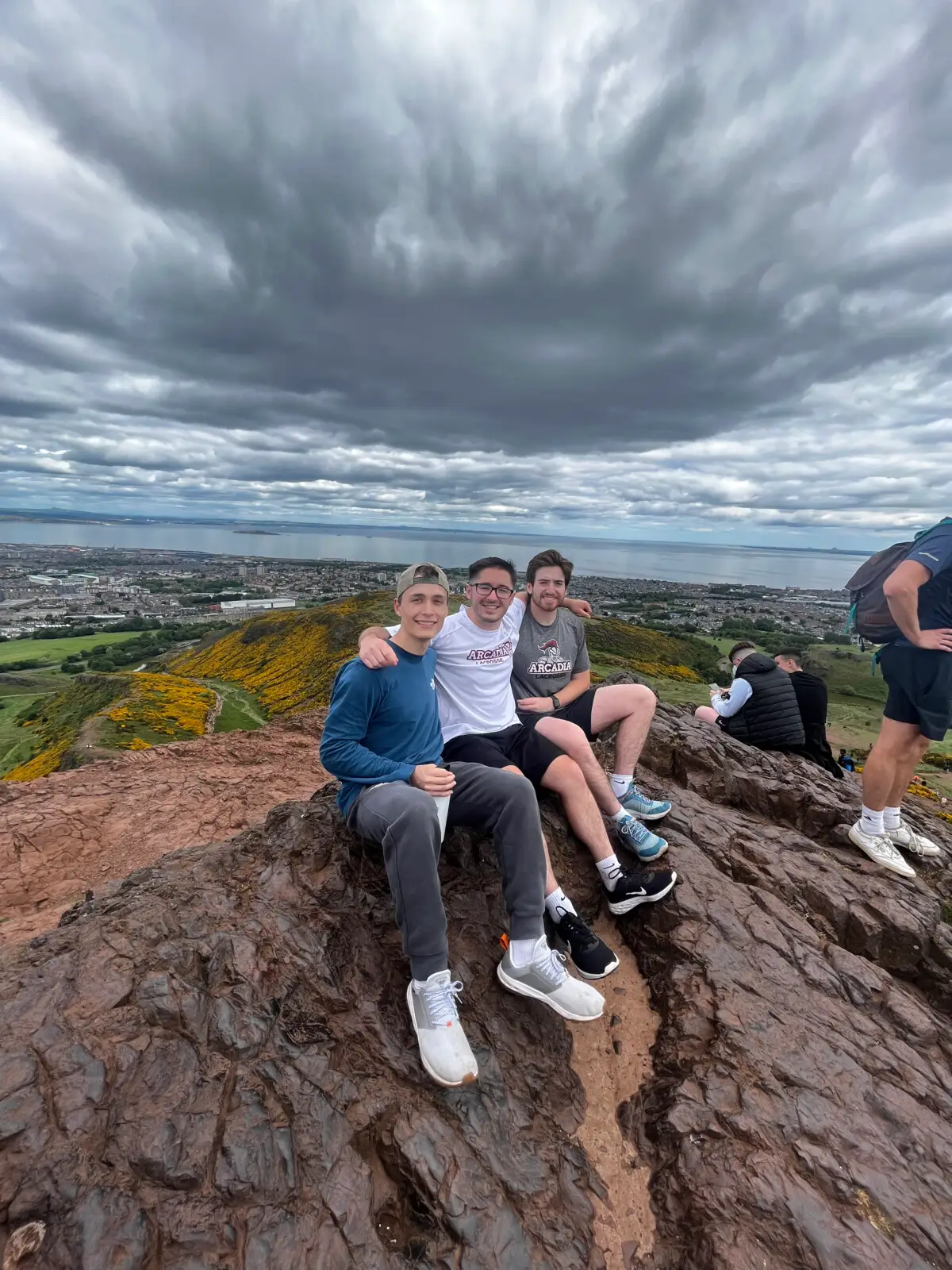 Patrick Ensmenger '23 with two friends seated on a large rock/cliff