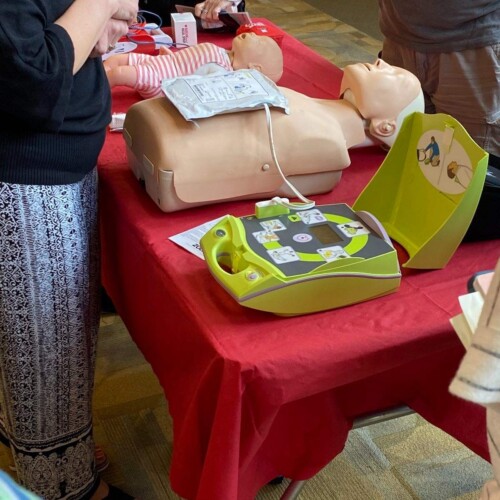 An AED sits open next to a dummy