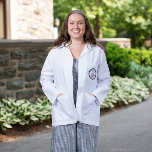 Martha Smee '25 MMS, MPH in a PA student white coat.