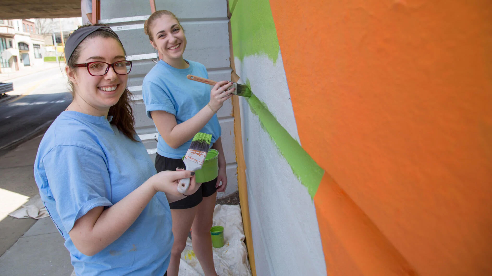 Two students painting a mural