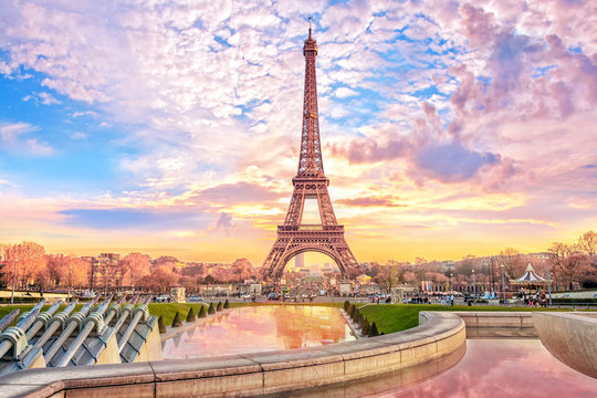 A view of the Eiffel Tower with sunny pinkish skies.