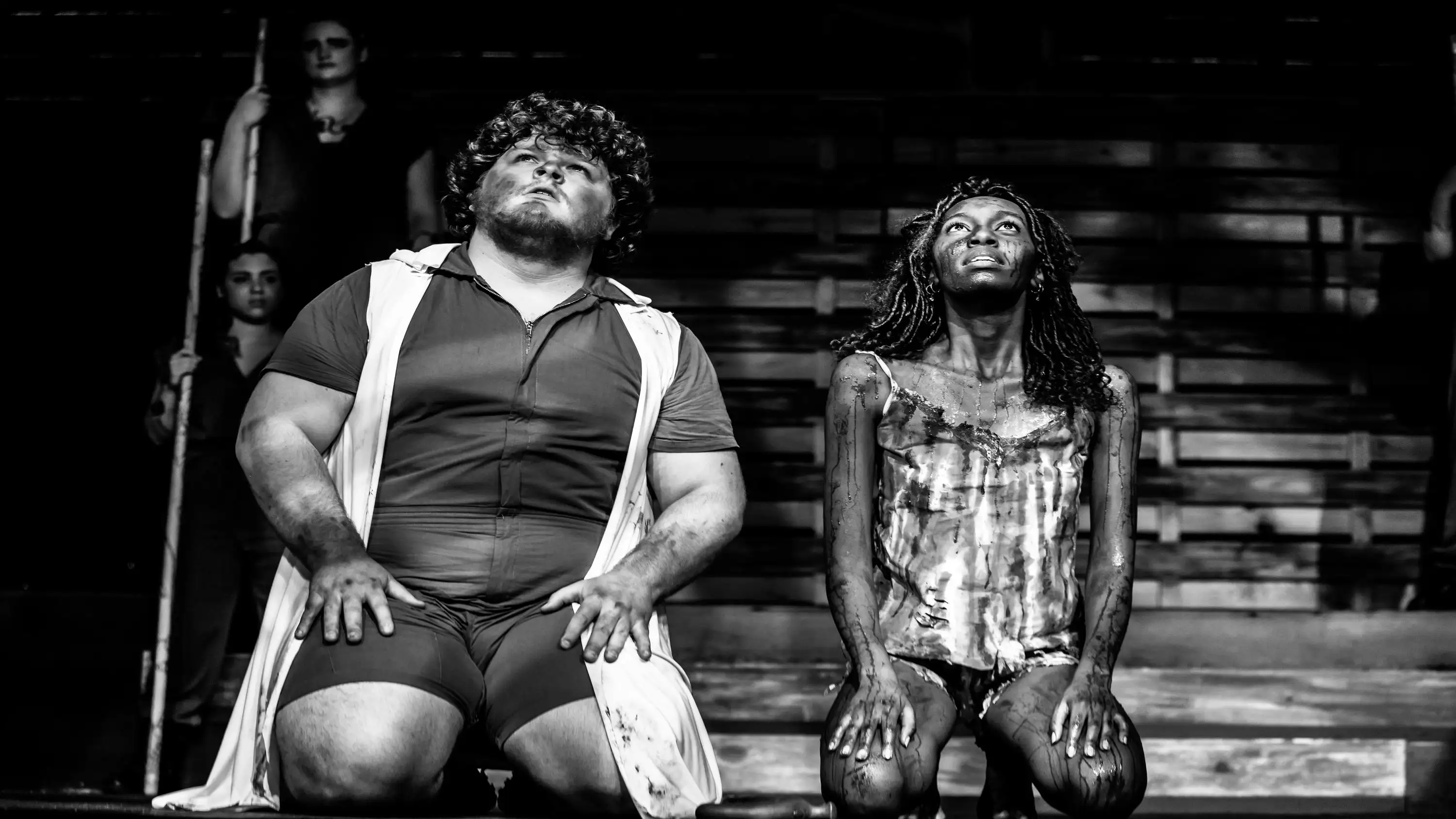 Greyscale photo by Daniel Kontz showing people covered in dirt kneeling down and looking up.