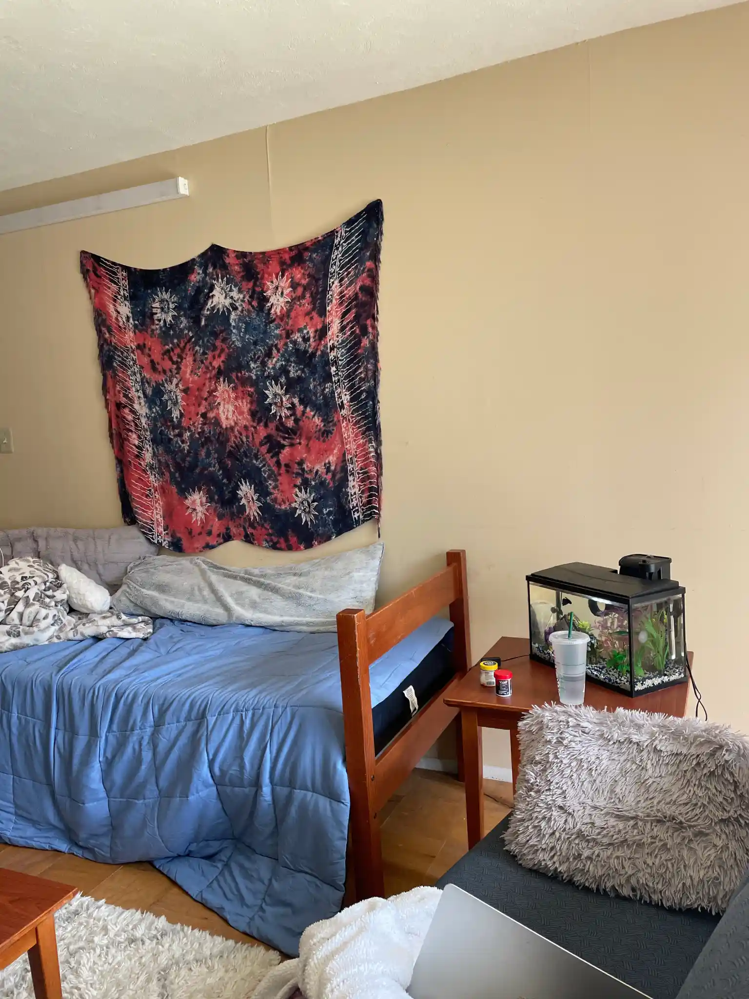 A bedroom with a tapestry on the wall.