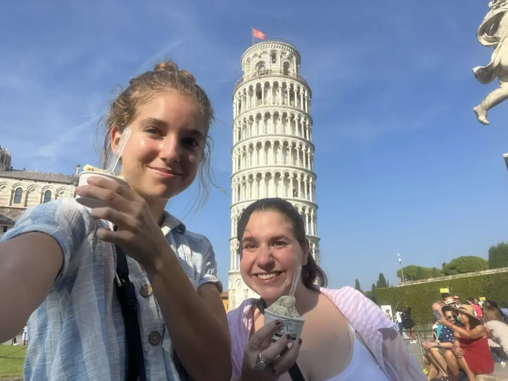 Sophie and her friend having ice cream with the leaning tower of Pisa behind them.