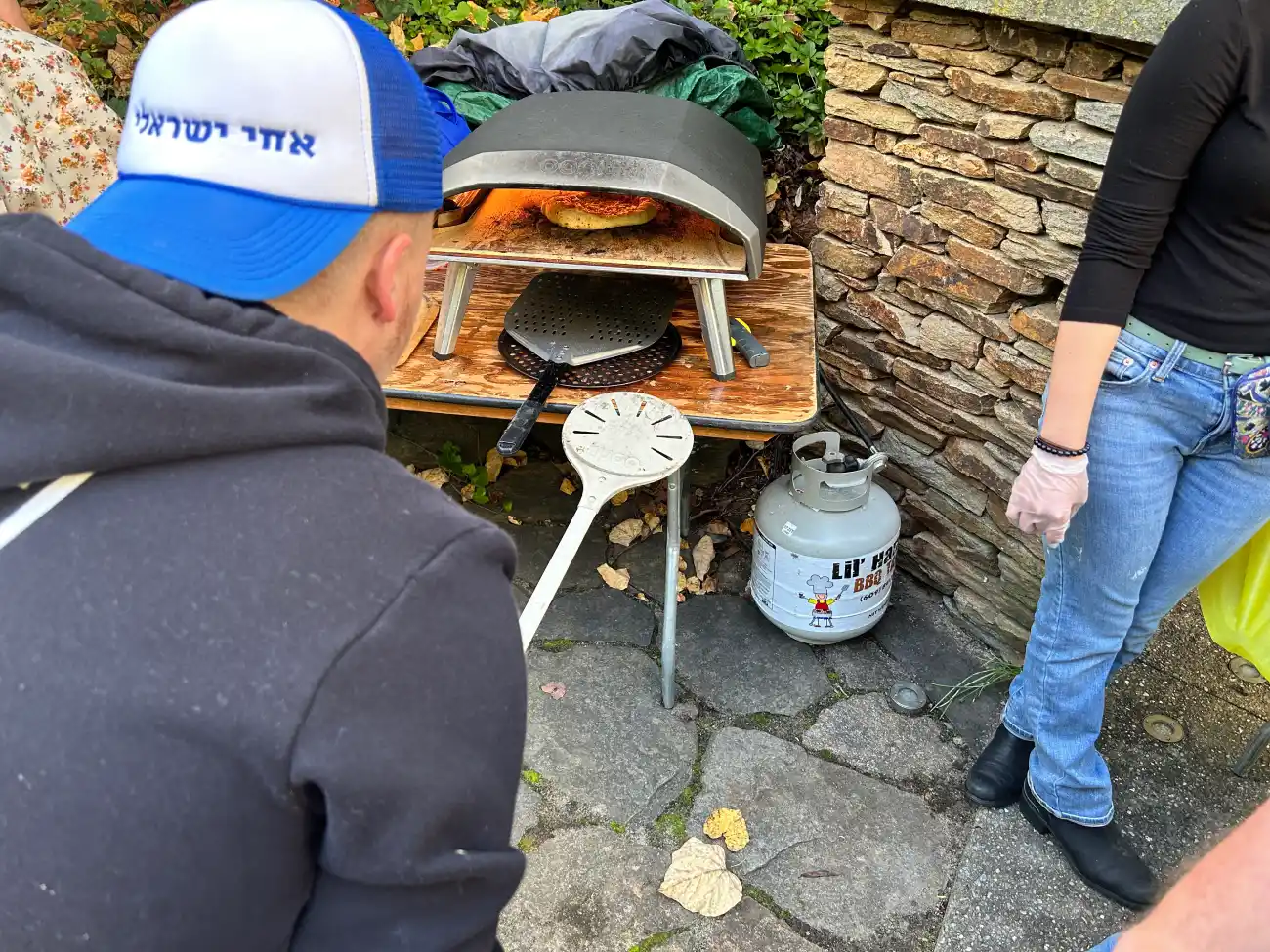 A student watching a pizza cook in the outdoor pizza oven.