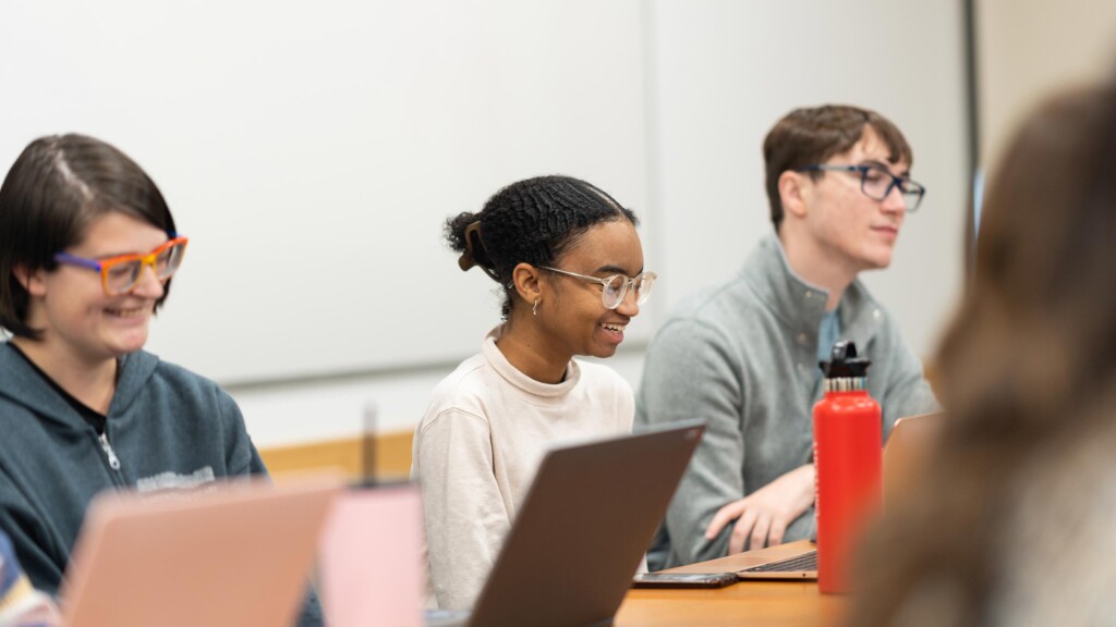 An undergraduate student smiles as when takes notes on her computer during a HAPS class.