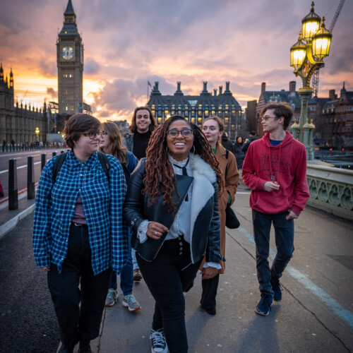 Students crossing a bridge in London at sunset.