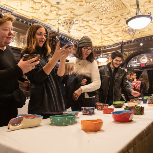 People looking at the different bowls offered at the Empty Dinner Bowl Dinner.