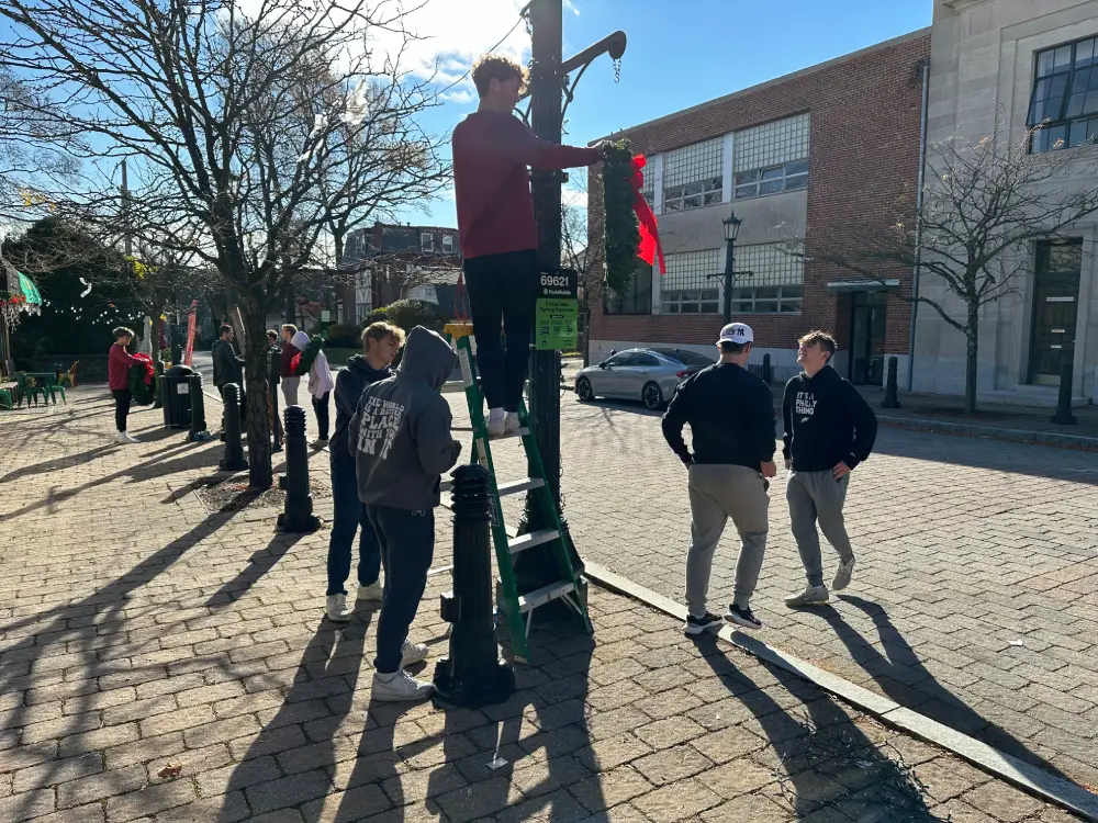 Students hanging a wreath on a lamp post.