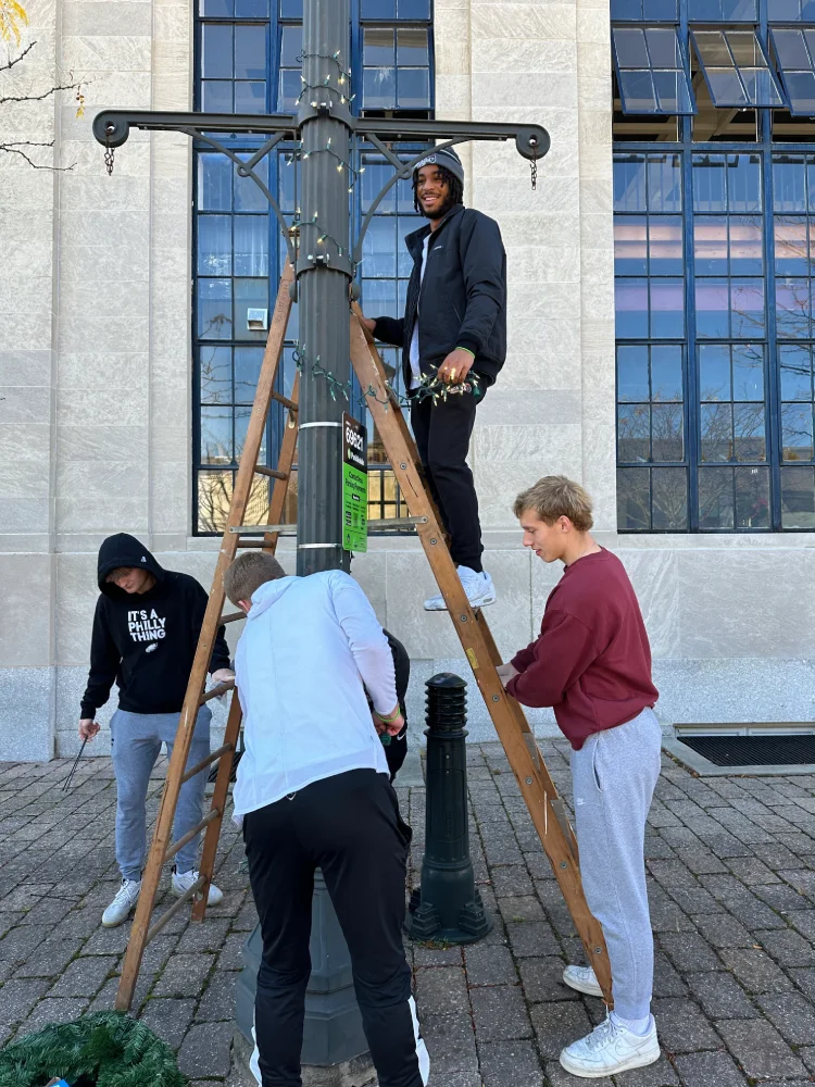 Students hanging lights on a lamp post.