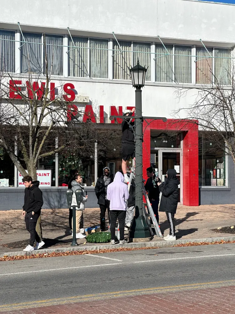 Students hanging lights on a lamp post.