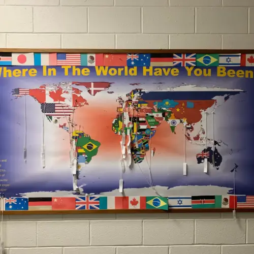 A bulletin board with a map of the world reading "Where in the World Have You Been?"