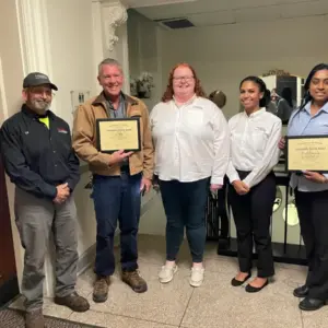 Staff from Arcadia's Facilities Management team stand together holding the Community Service Award they received from the township commissioners