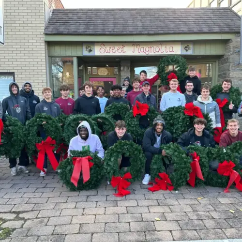 Judge Cerski and the Men's Soccer Team holding wreaths.