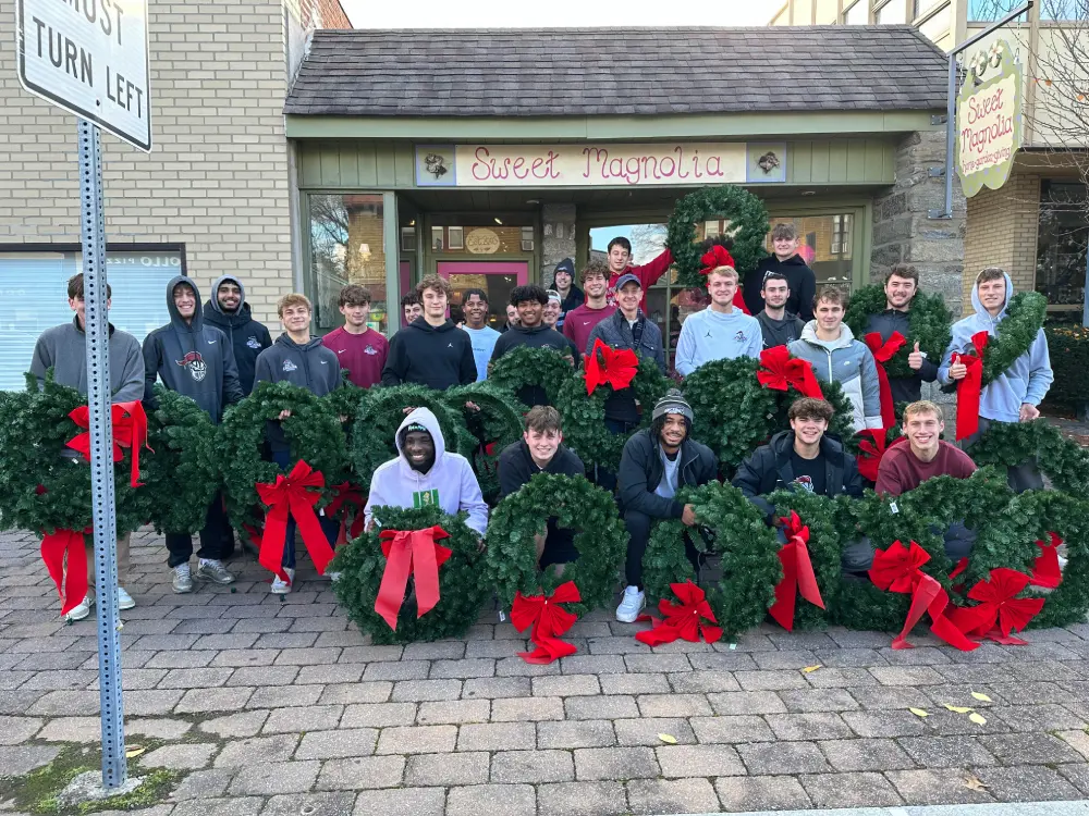 Judge Cerski and the Men's Soccer Team holding wreaths.