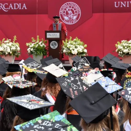 President addresses undergraduates seated and wearing their cap and gowns.