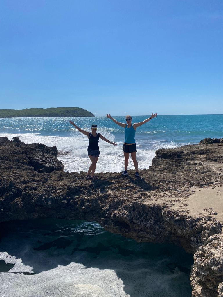 Two people posing on the rocks by the ocean.