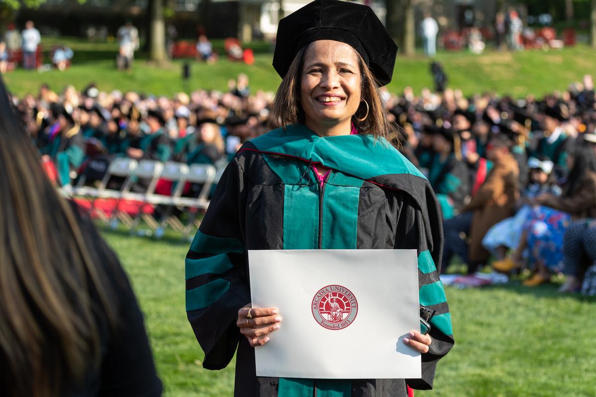 A student smiling during during the graduate commencement on Haber Green.