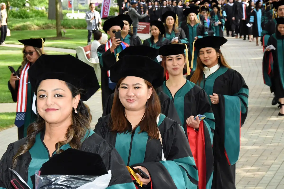 Students smiling during during the graduate commencement on Haber Green