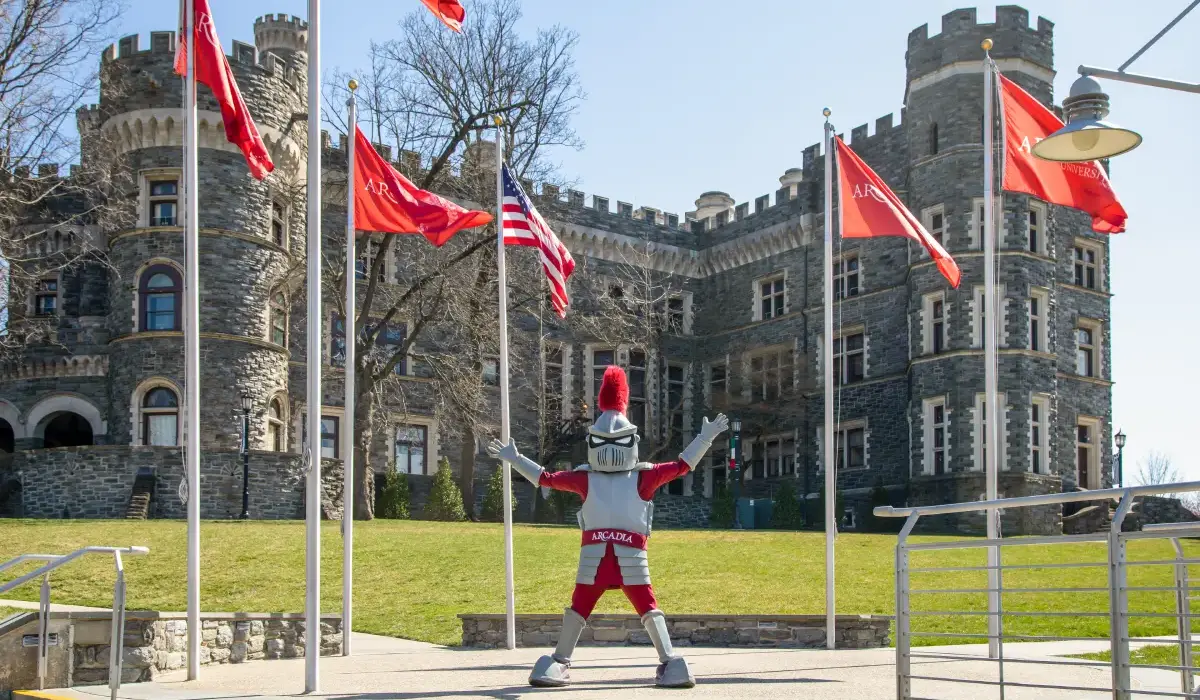 Knight Mascot in front of Arcadia flags with Grey Towers Castle in the background